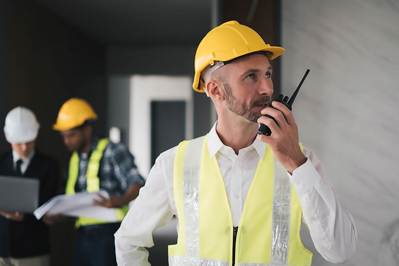 professional-engineers-construction-radio Construction engineers using radios to maintain site safety and project coordination.